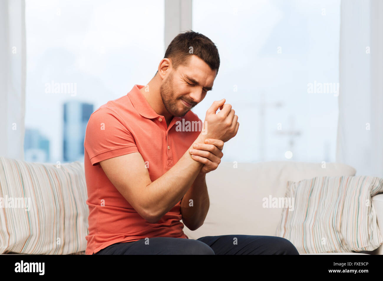 unhappy man suffering from pain in hand at home Stock Photo - Alamy