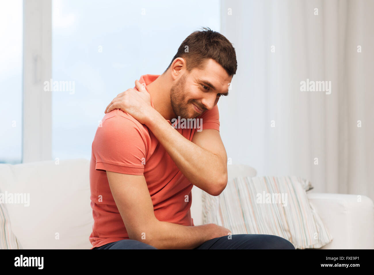unhappy man suffering from neck pain at home Stock Photo - Alamy