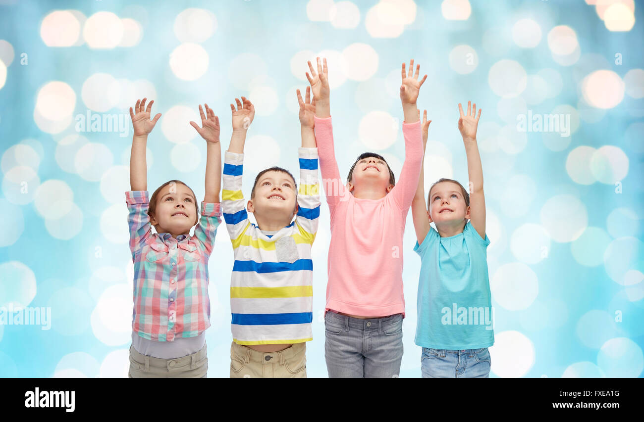 happy children with raised hands over blue lights Stock Photo - Alamy