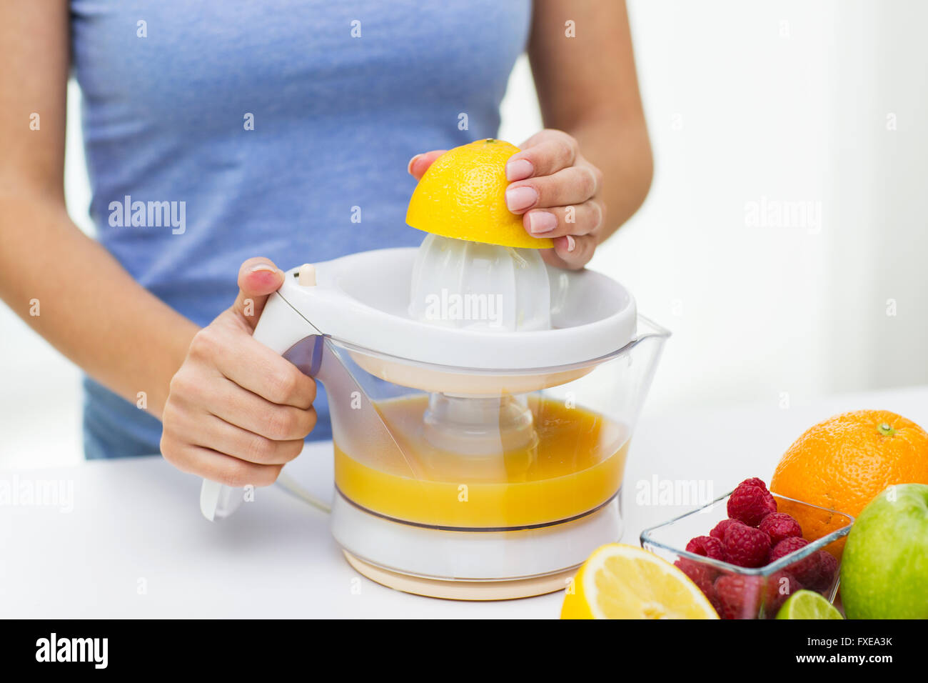 close up of woman squeezing fruit juice at home Stock Photo