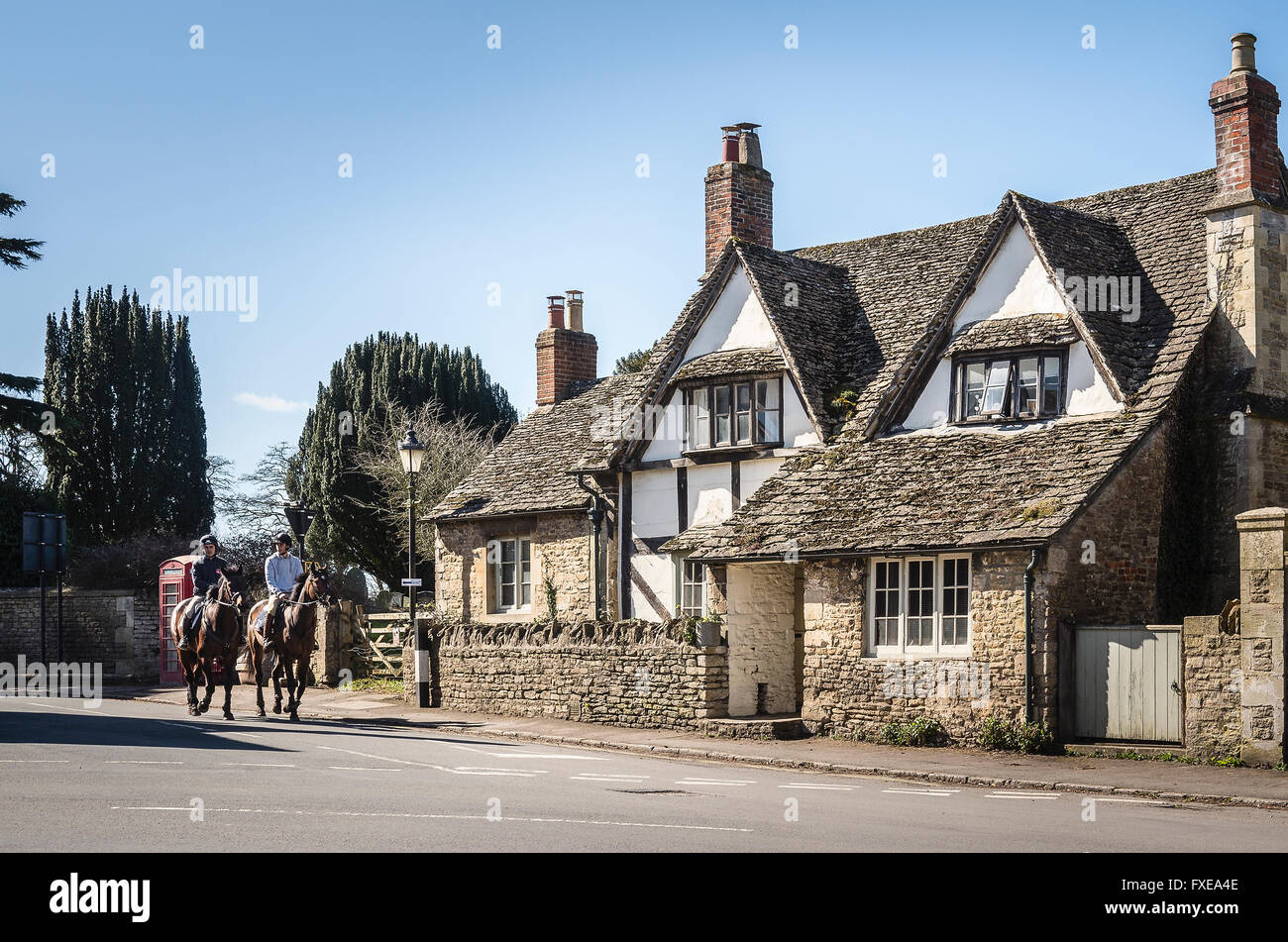Horse riders entering Lacock village in Wiltshire UK Stock Photo