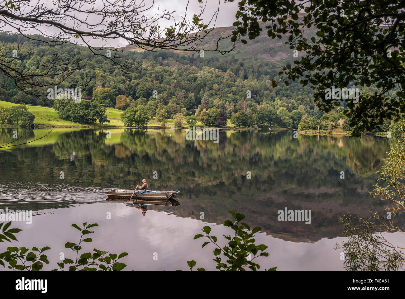 A lone angler in his boat on Grasmere in the Lake District. Cumbria. North West England. Stock Photo