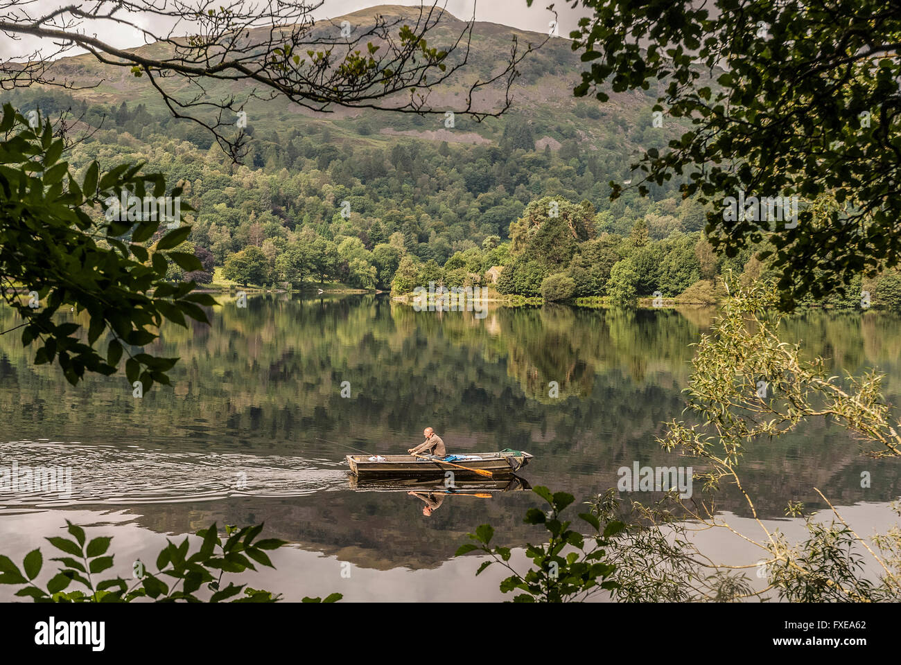 A lone angler in his boat on Grasmere in the Lake District. Cumbria. North West England. Stock Photo