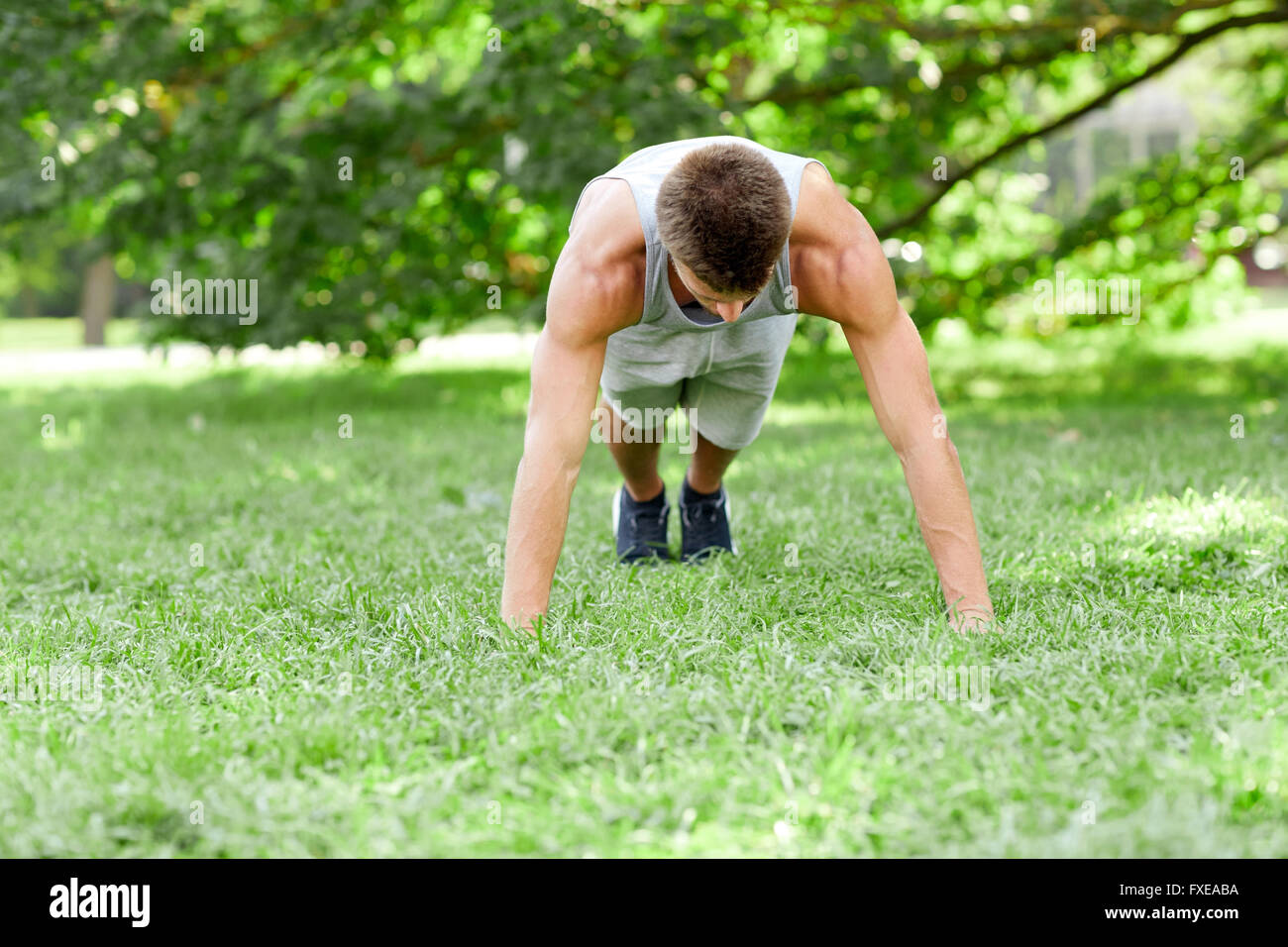 young man doing push ups on grass in summer park Stock Photo - Alamy