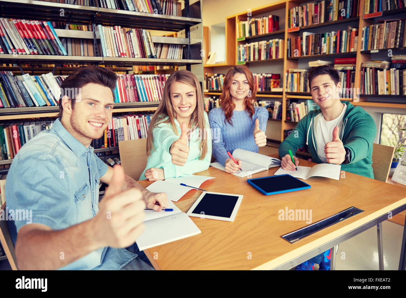 happy students showing thumbs up in school library Stock Photo - Alamy