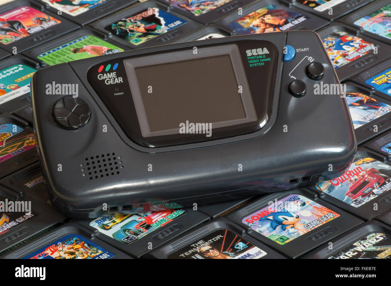 The Sega Game Gear portable video game system on a bed of video game cartridges including Sonic the Hedgehog and Star Wars Stock Photo