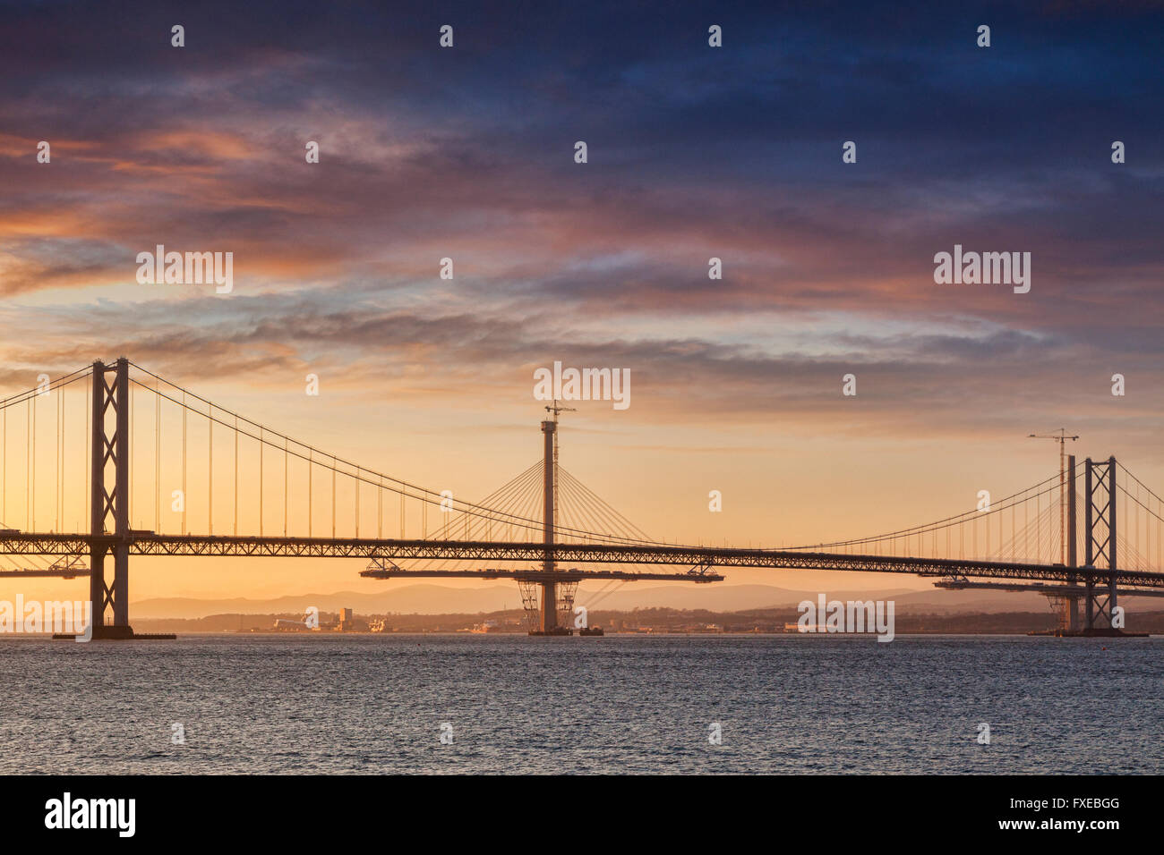 The Forth Road Bridge at sunset, with the Queensferry Crossing under construction behind it, Edinburgh, Scotland, UK Stock Photo