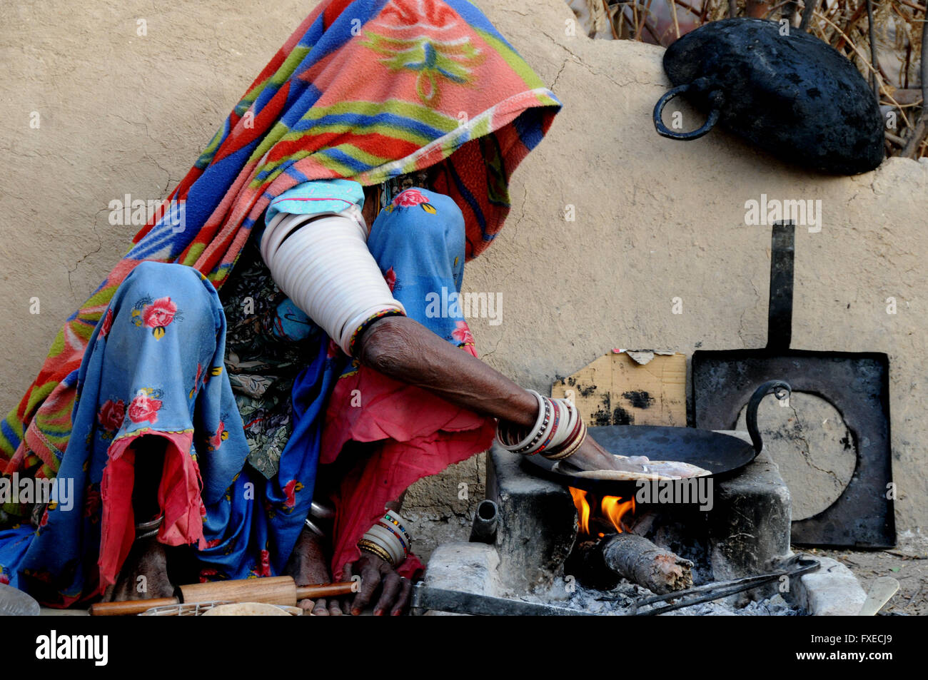 A woman sits making her early morning breakfast chapatis in a village near the northern Indian town of Jojawar. Stock Photo