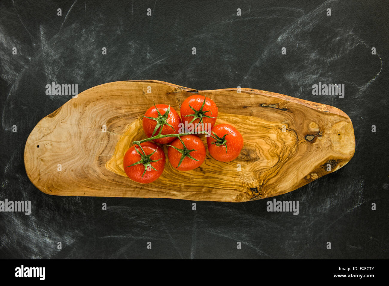 Bunch of tomatoes on wooden cutting board. Stock Photo