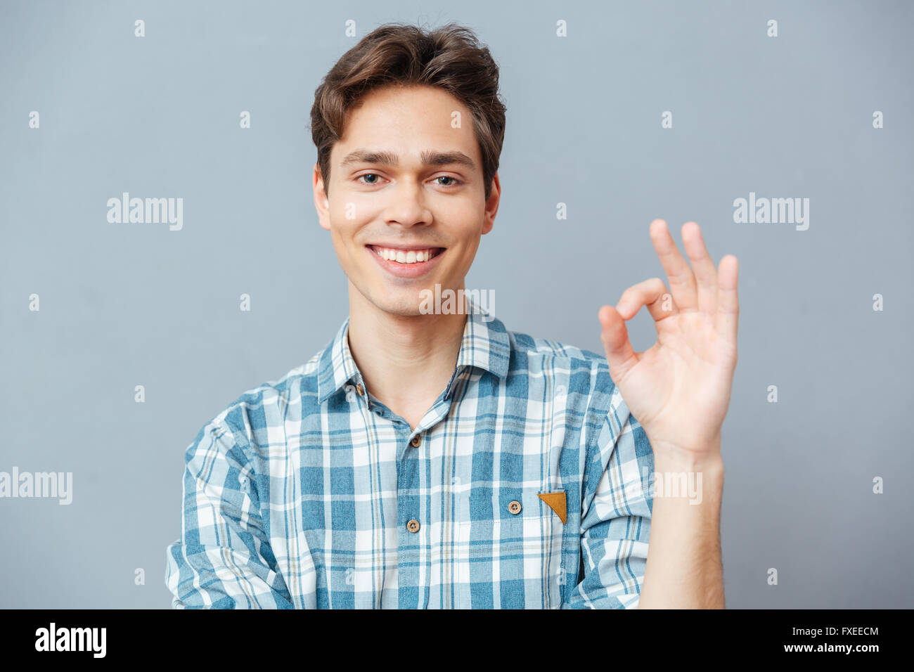 Happy man showing ok sign with fingers over gray background Stock Photo ...