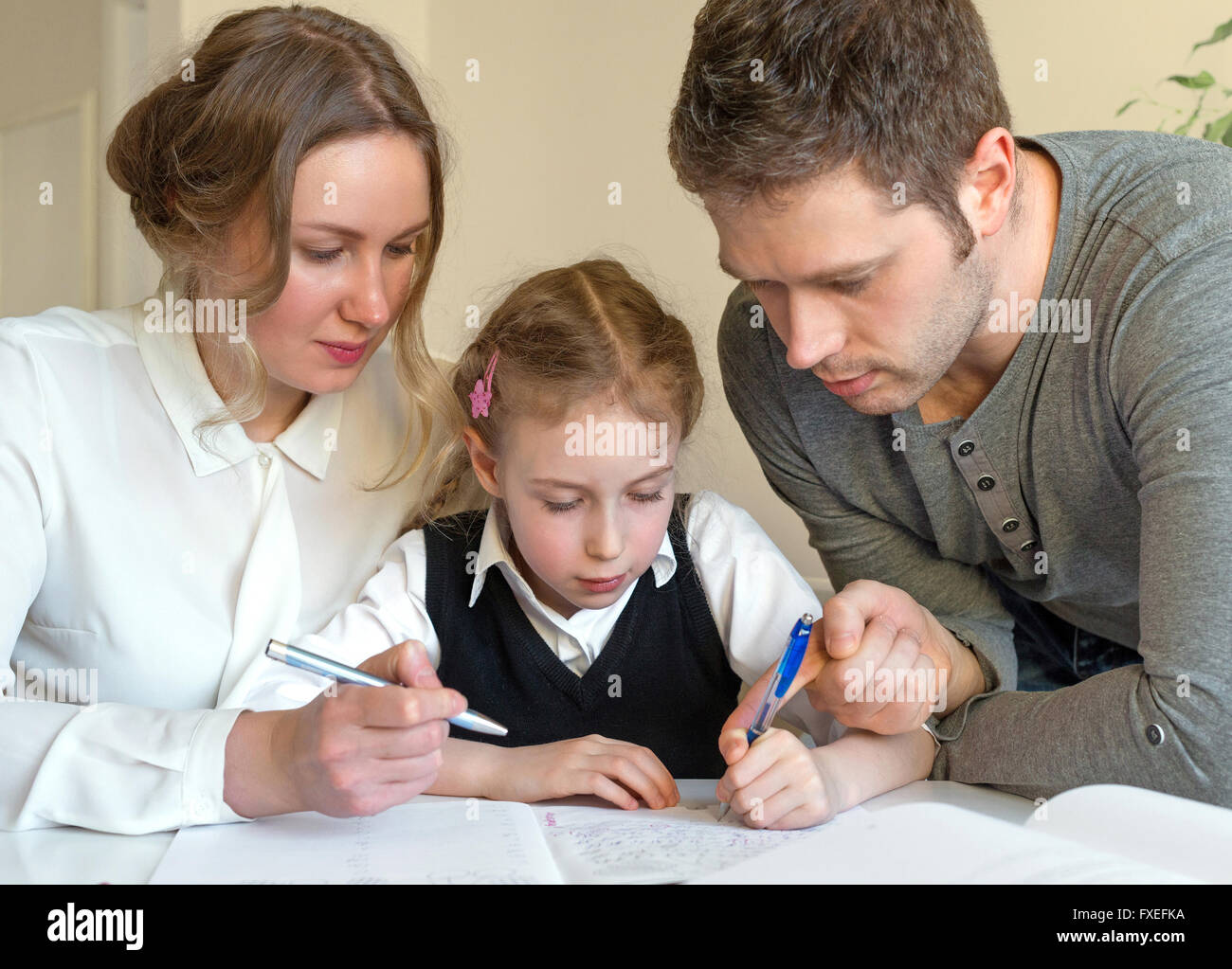Mother and father helping daughter with homework at home Stock Photo ...