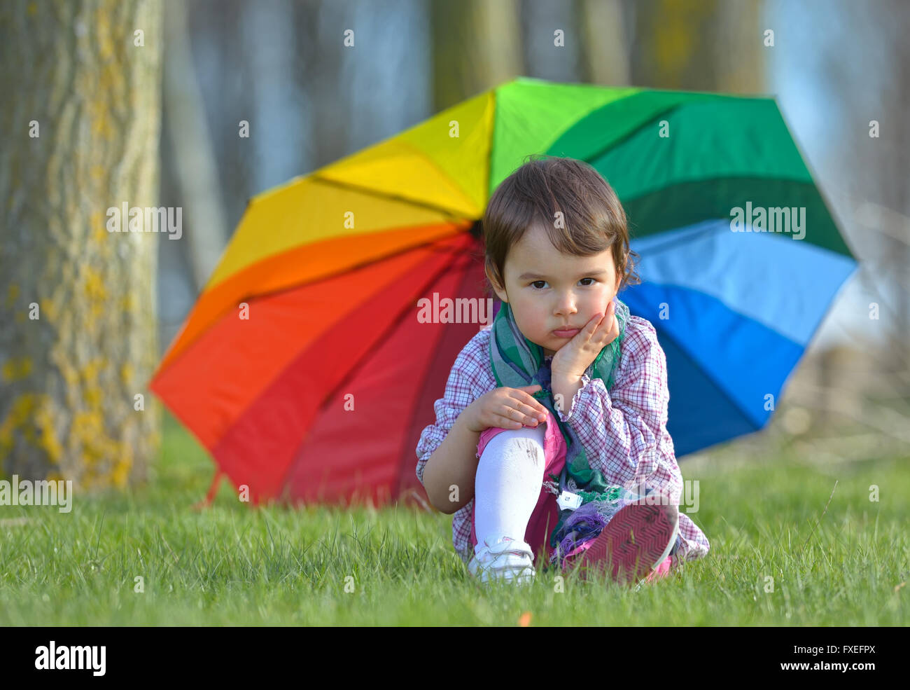 A little girl with a rainbow umbrella in forest Stock Photo