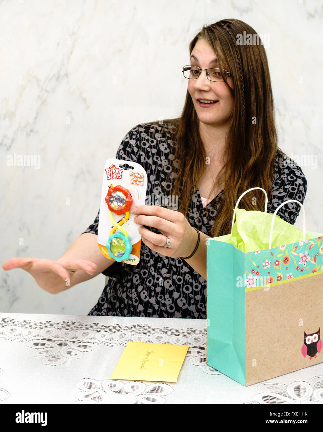 A Caucasian expectant mother in her 20s opens baby gifts at her baby shower. USA. Stock Photo