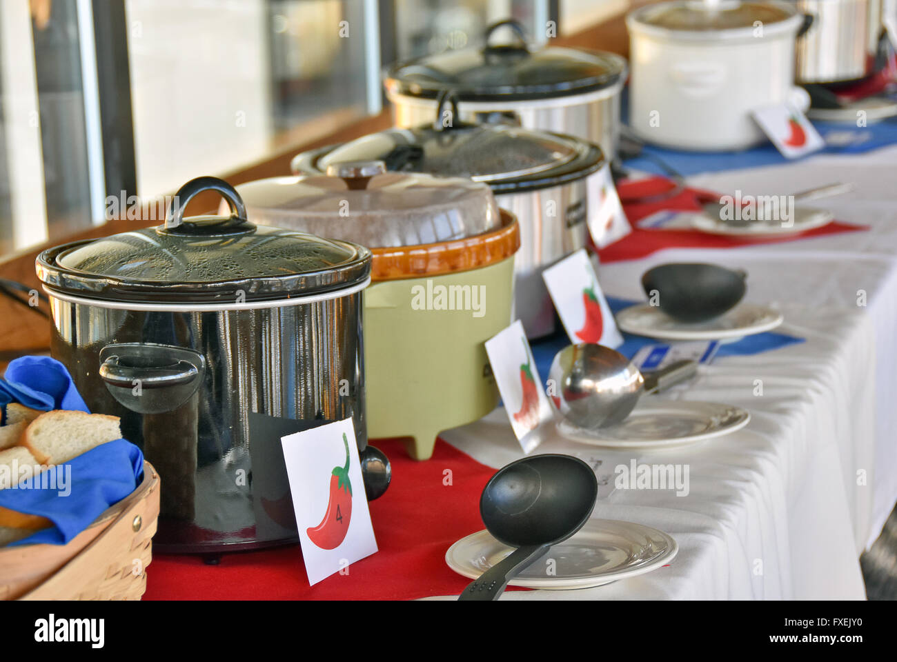 Row of crock pots with ladles in a chili cook-off contest in a restaurant. Stock Photo