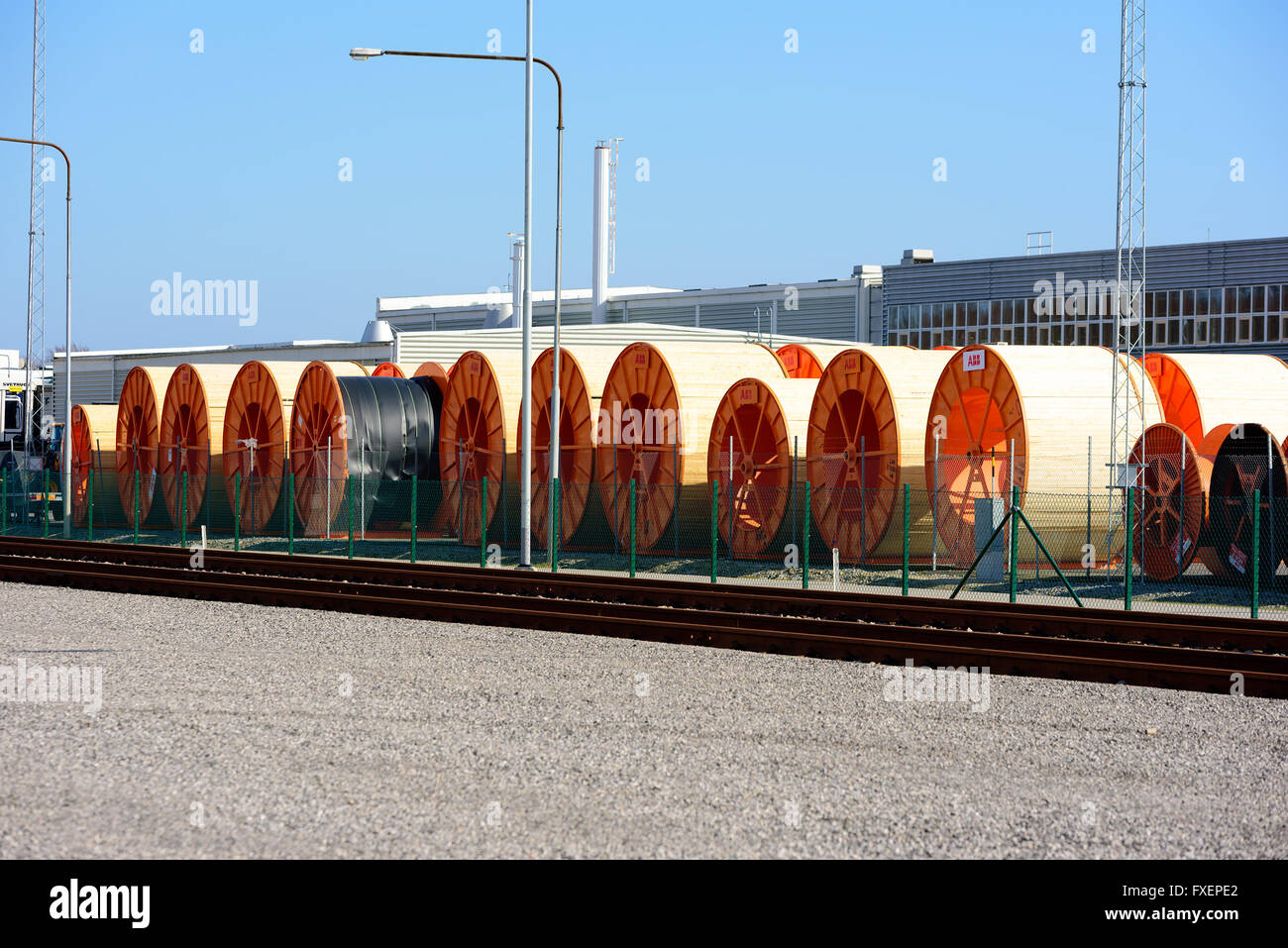 Karlskrona, Sweden - April 7, 2016: Large high voltage cable cylinders stored outdoors on industrial area. Building in backgroun Stock Photo