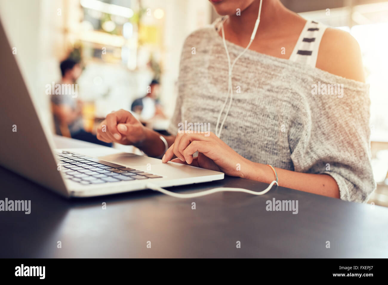 Cropped image of young woman using laptop at coffee shop. Close up portrait of woman working on laptop computer, with focus on l Stock Photo