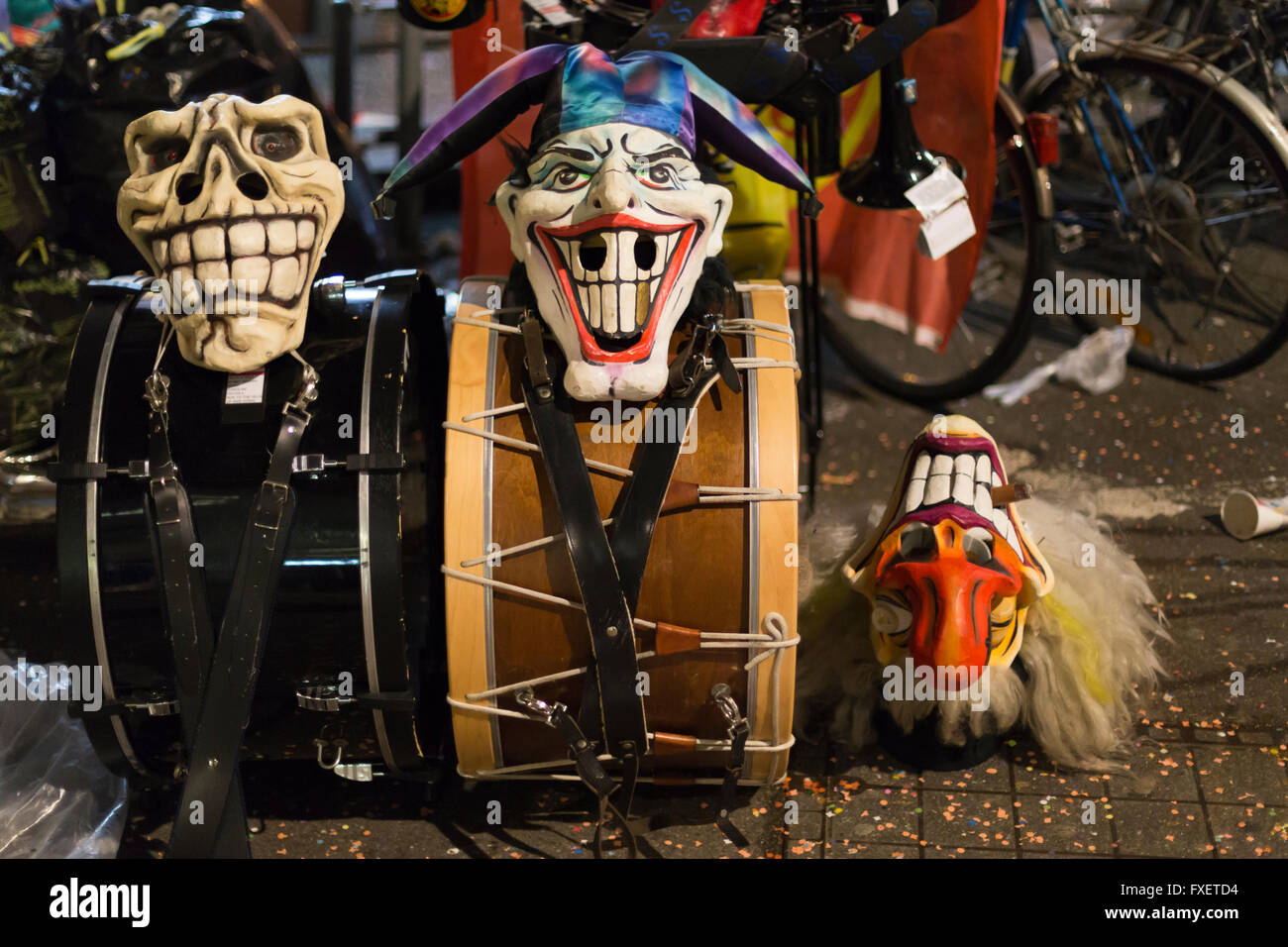Close view on three grinning Basel carnival masks laying on top of two big drums and on the street. Stock Photo