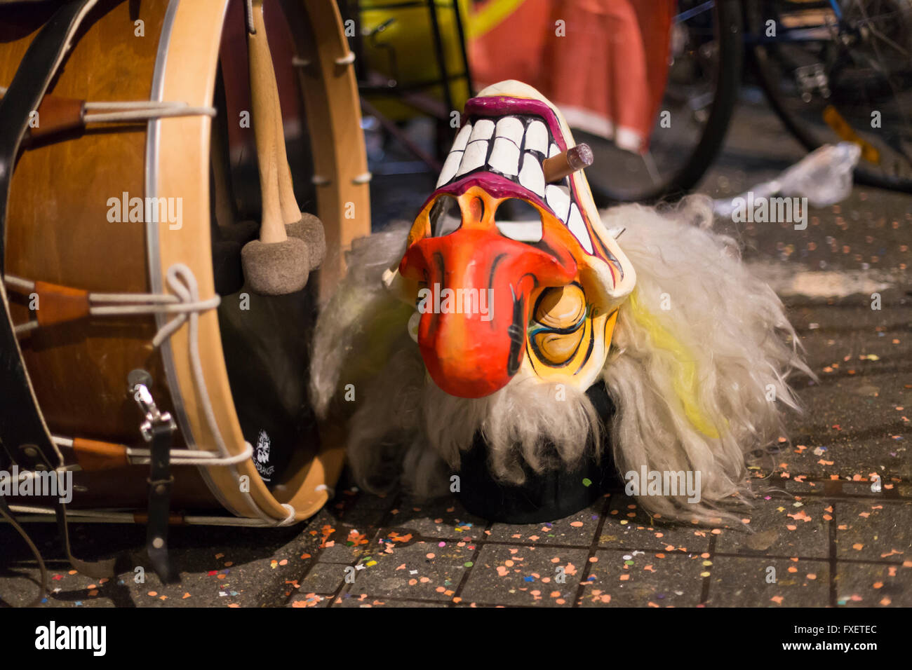 Close view on one grinning Basel carnival mask laying on the street besides a big drum. Stock Photo
