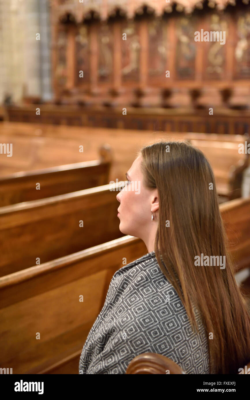 Side view of woman sitting in pews of cathedral Stock Photo