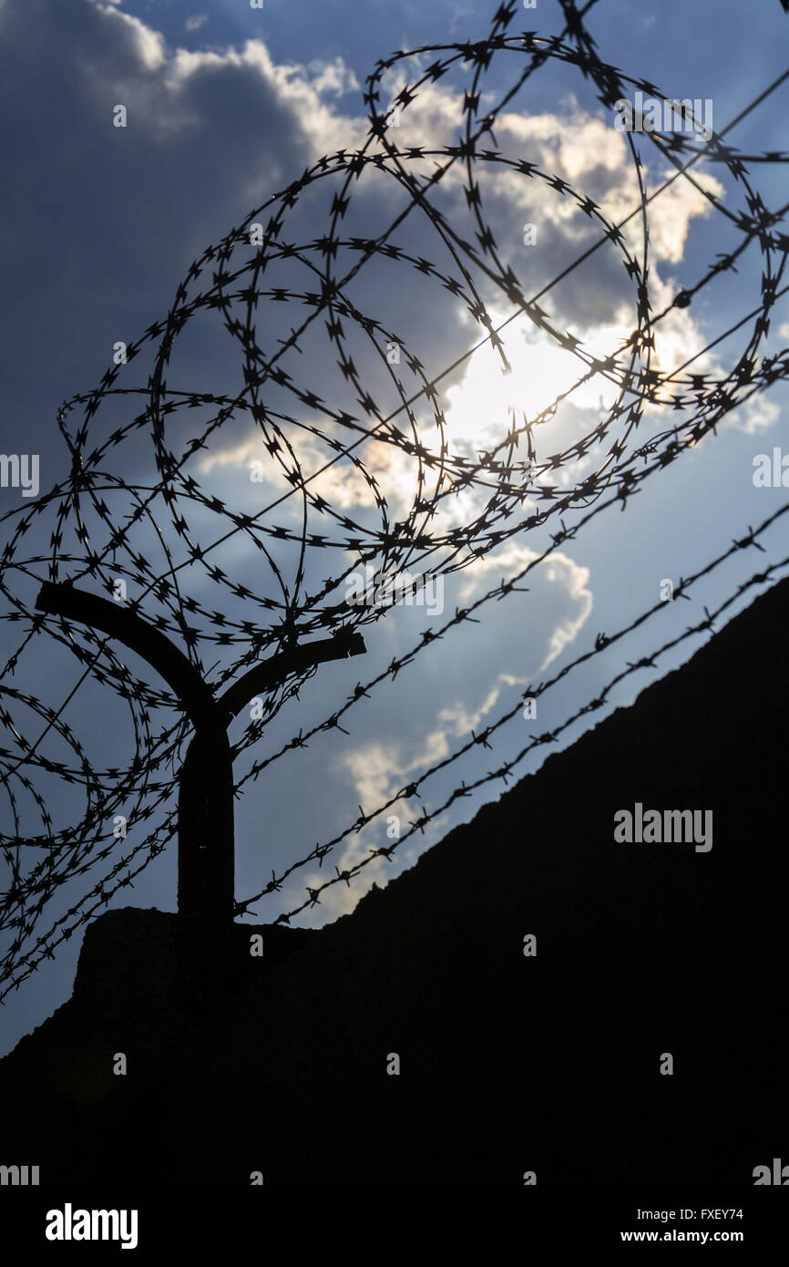 Dramatic clouds behind barbed wire fence on a prison wall Stock Photo ...