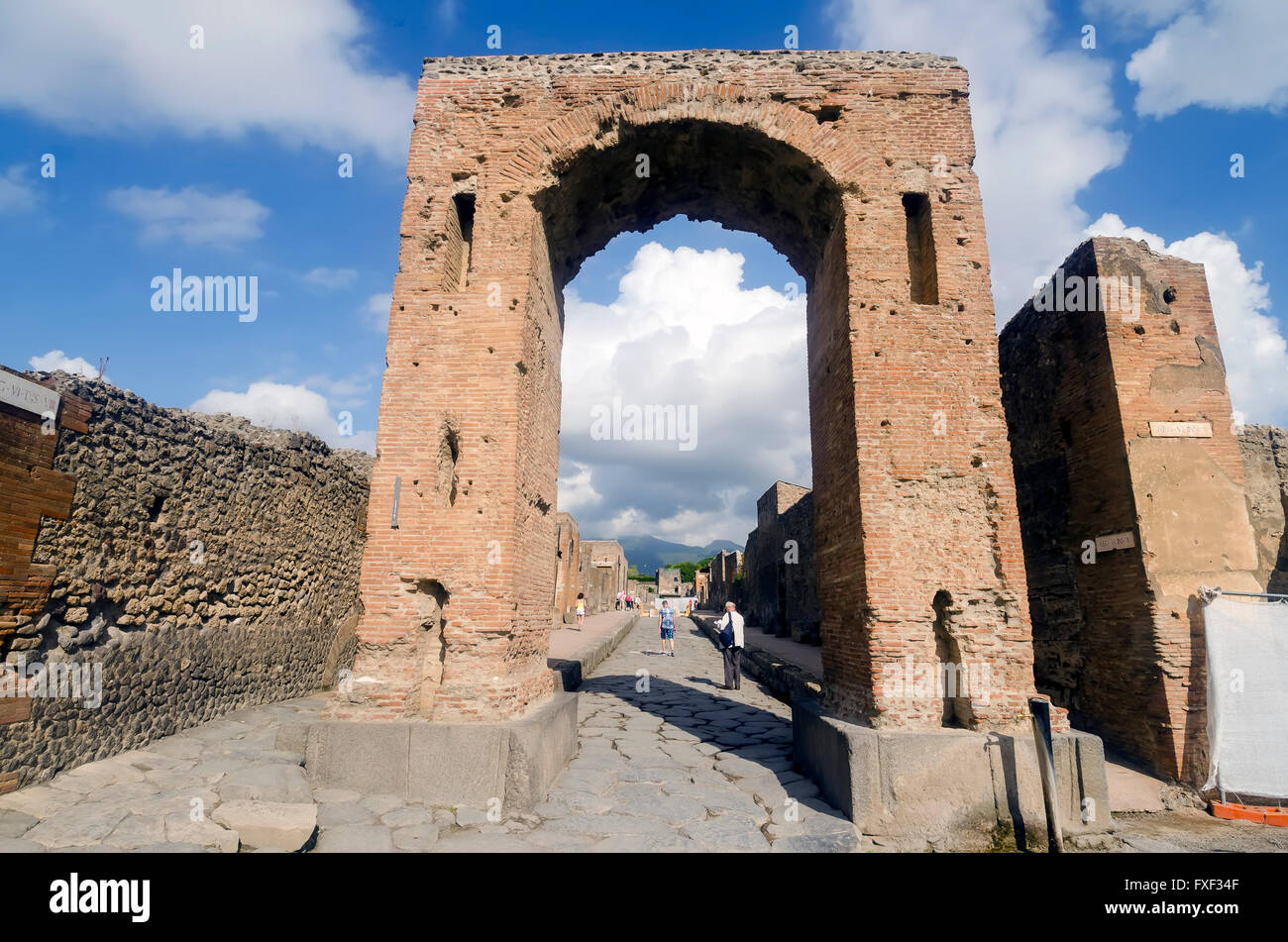 Toutists walking through Arch of Caligula at the start of the Via Mercurio, Mount Vesuvius in background, Pompeii Iraly Stock Photo