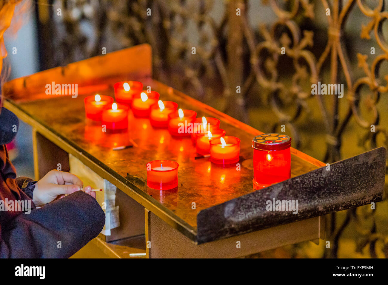 red candles in Catholics church while young girl is holding a match