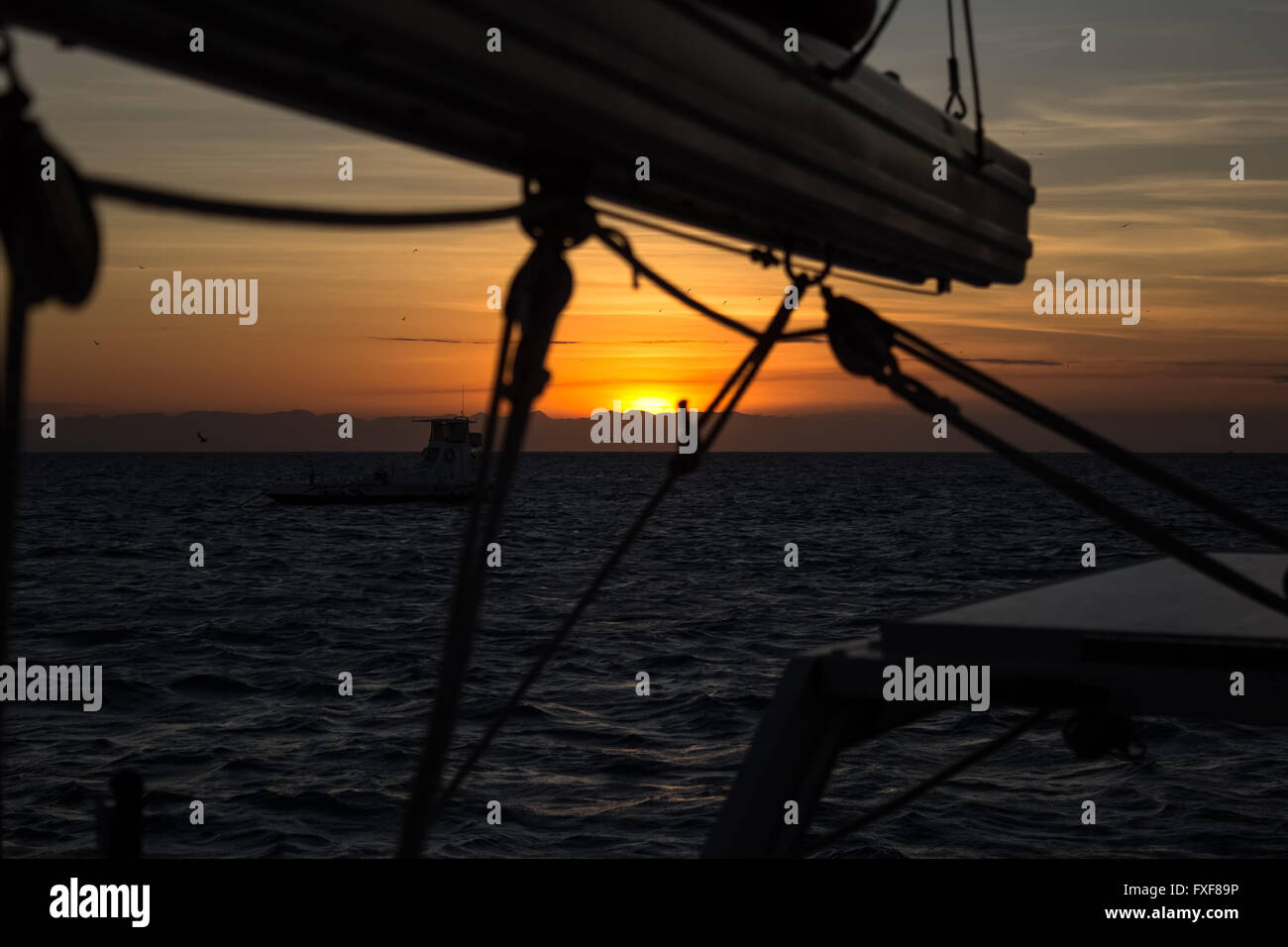 The sun sets into the coast. View from a Sailingboat anchored at Lizard Island, Queensland, Australia Stock Photo