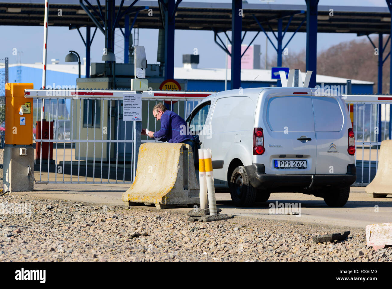 Karlskrona, Sweden - April 7, 2016: Man standing by the gates to the ferry terminal entering a code to open the gate. He has pap Stock Photo