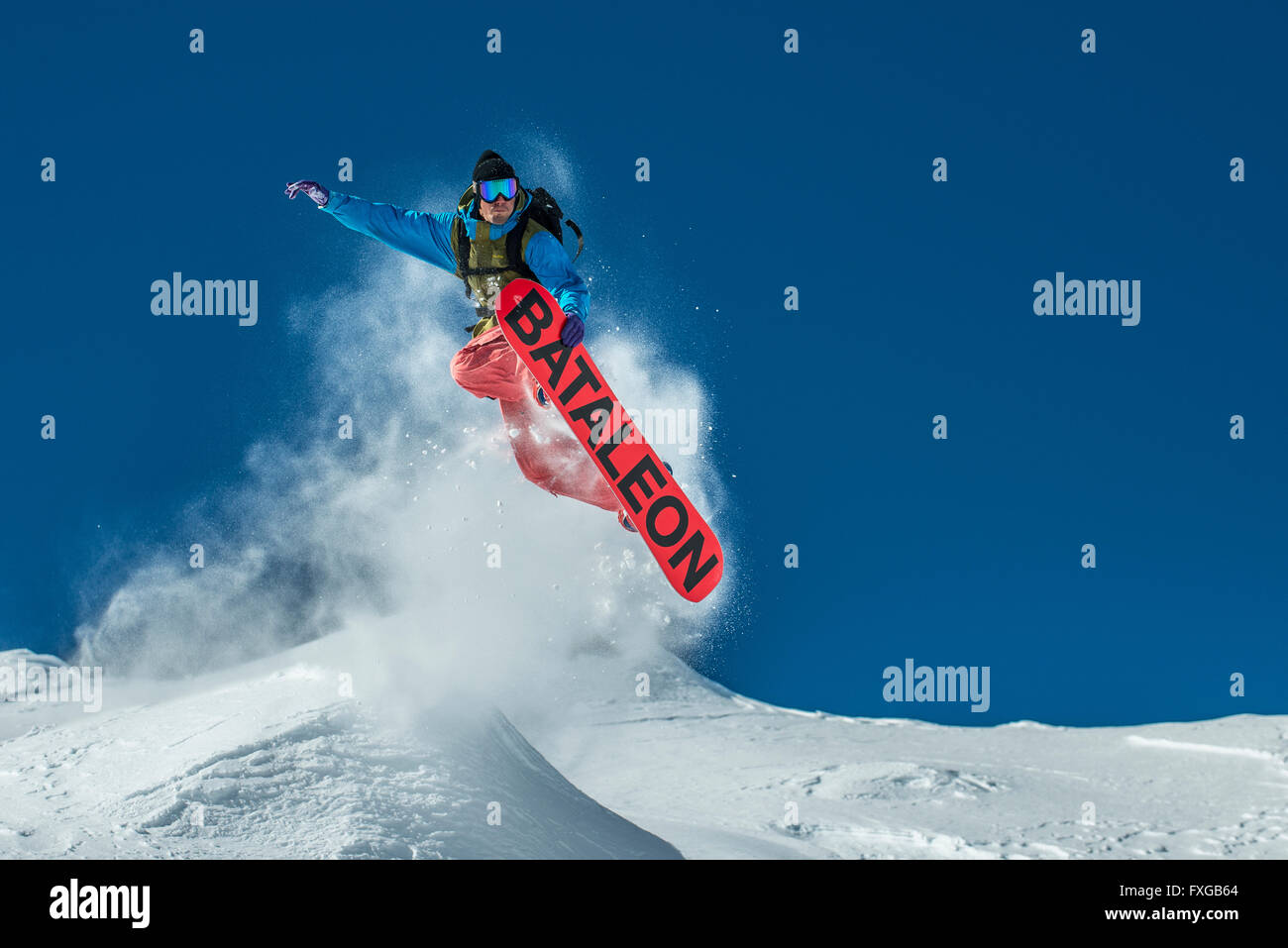 A snowboarder jumps off piste in powder snow in the French ski resort of Courchevel. Stock Photo