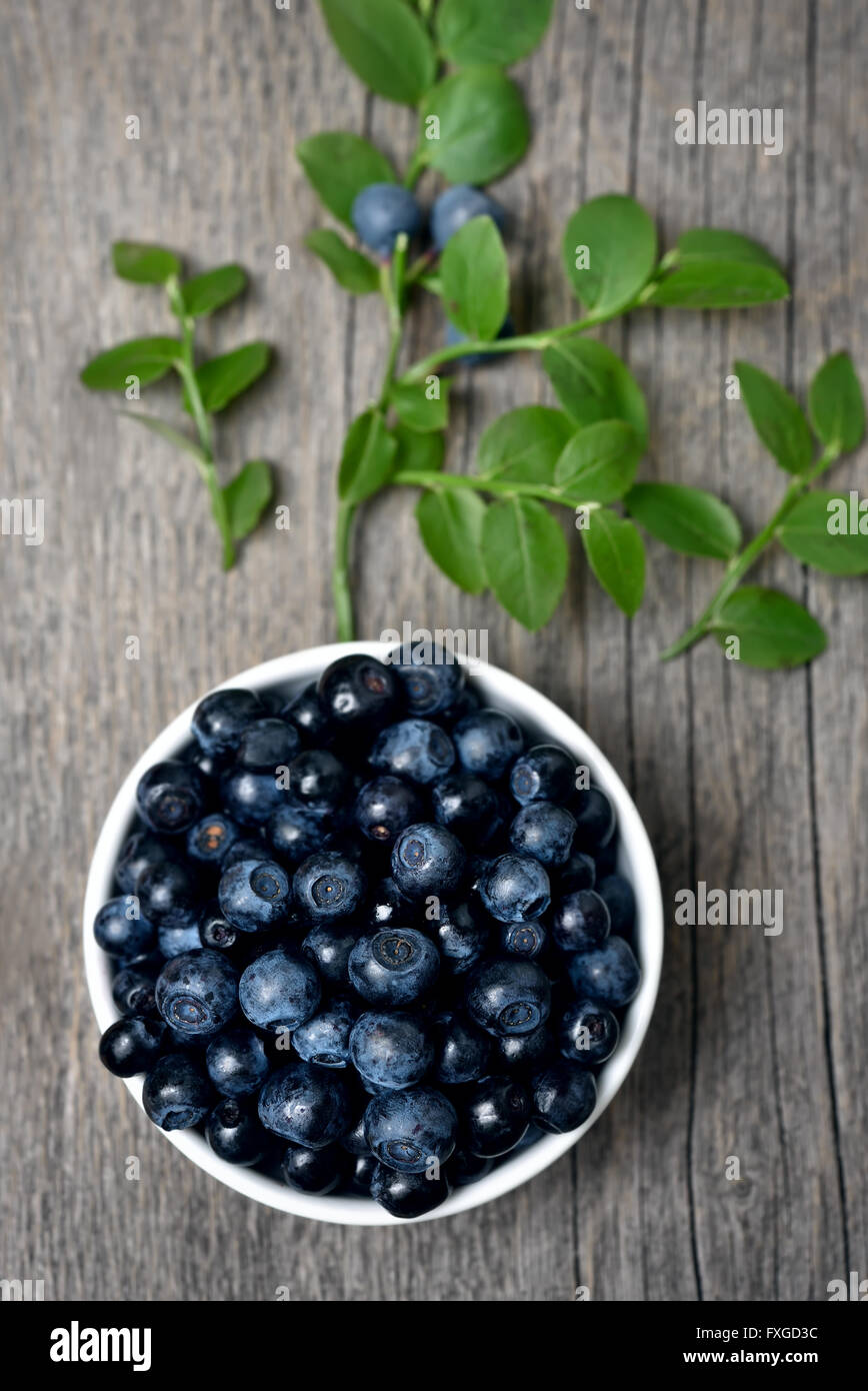 Fresh blueberries in bowl on wooden background, top view Stock Photo