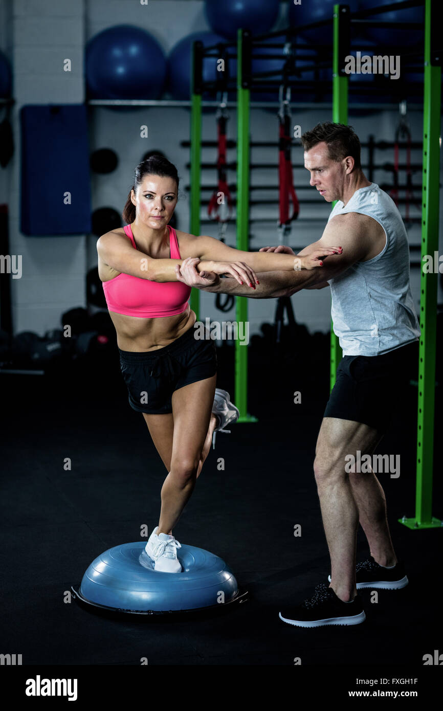 Trainer assisting a woman standing on a bosu ball Stock Photo Alamy