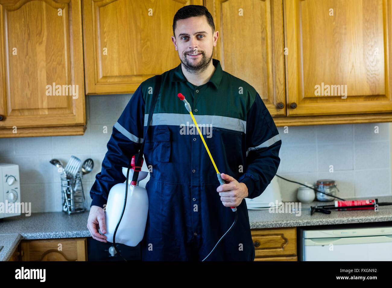 Portrait of pest control man spraying pesticide in kitchen Stock Photo