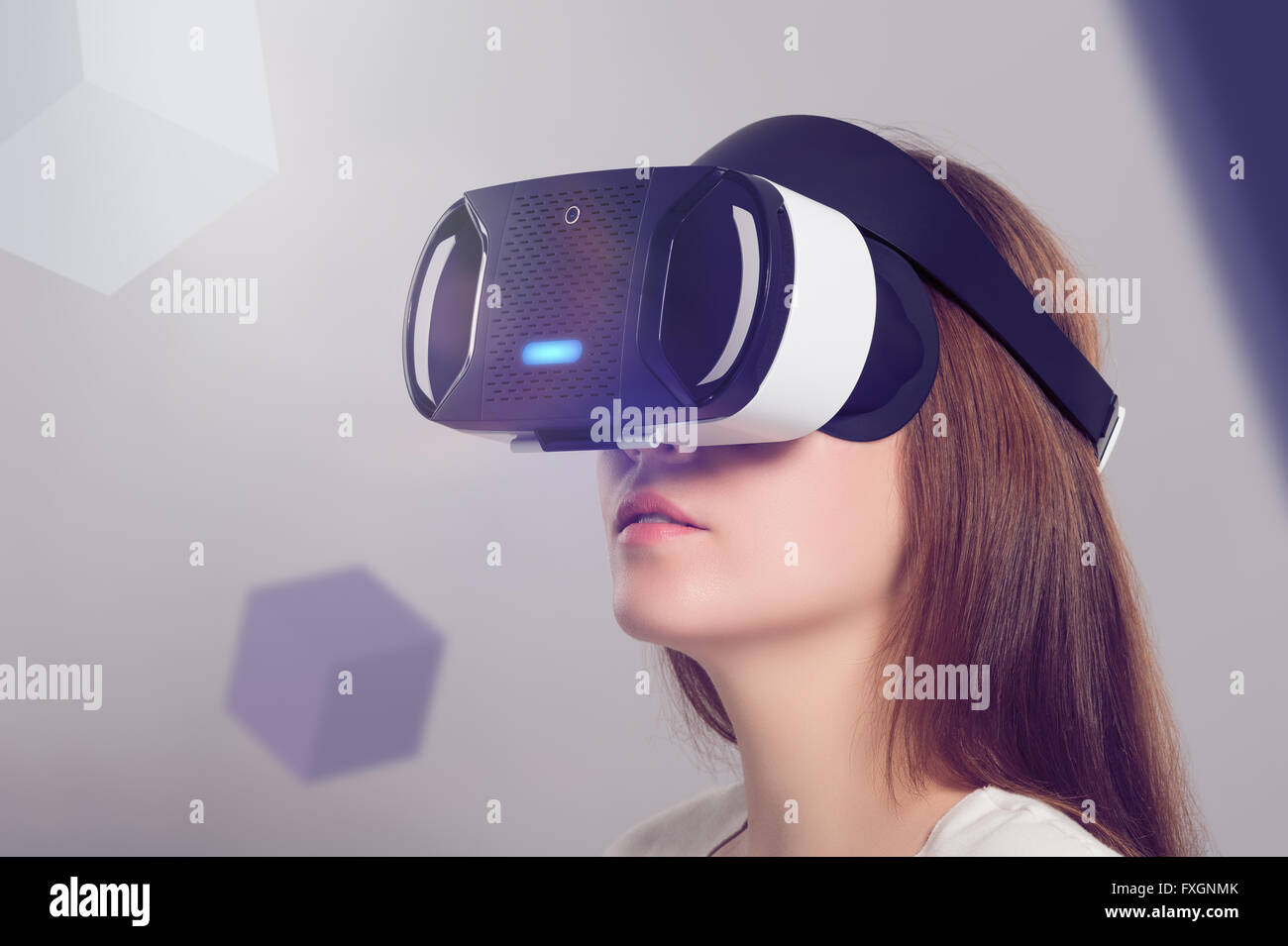 Woman in VR headset looking up at the objects in virtual reality. VR is a computer technology that simulates a physical presence Stock Photo