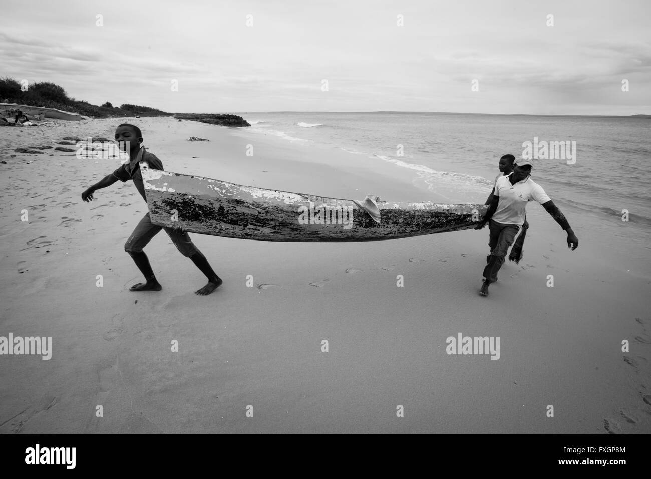 Mozambique, Africa, a fishermen taking the boat out of the sea, white beach, black and white. Stock Photo