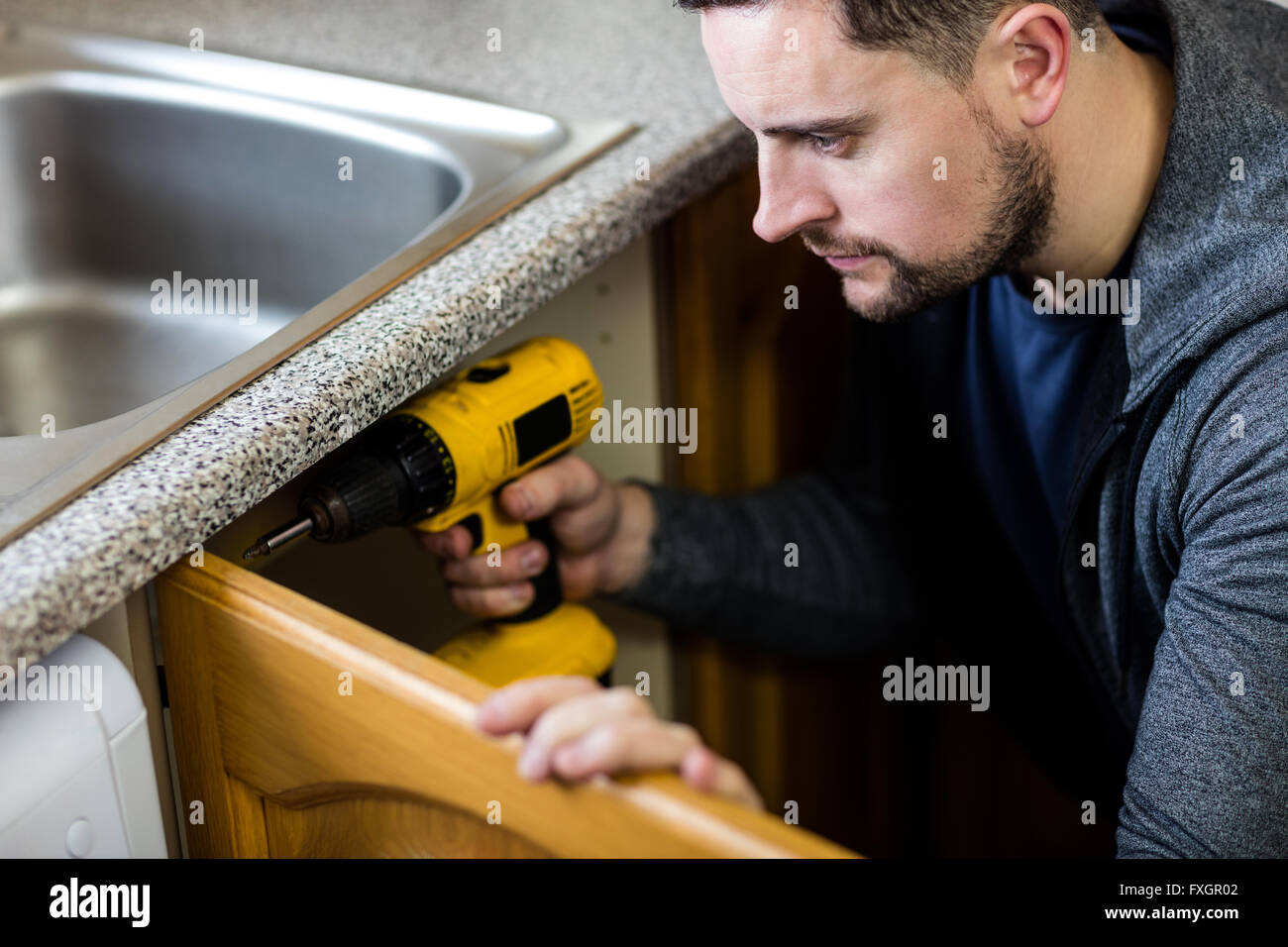 Manual worker drilling a hole in kitchen Stock Photo