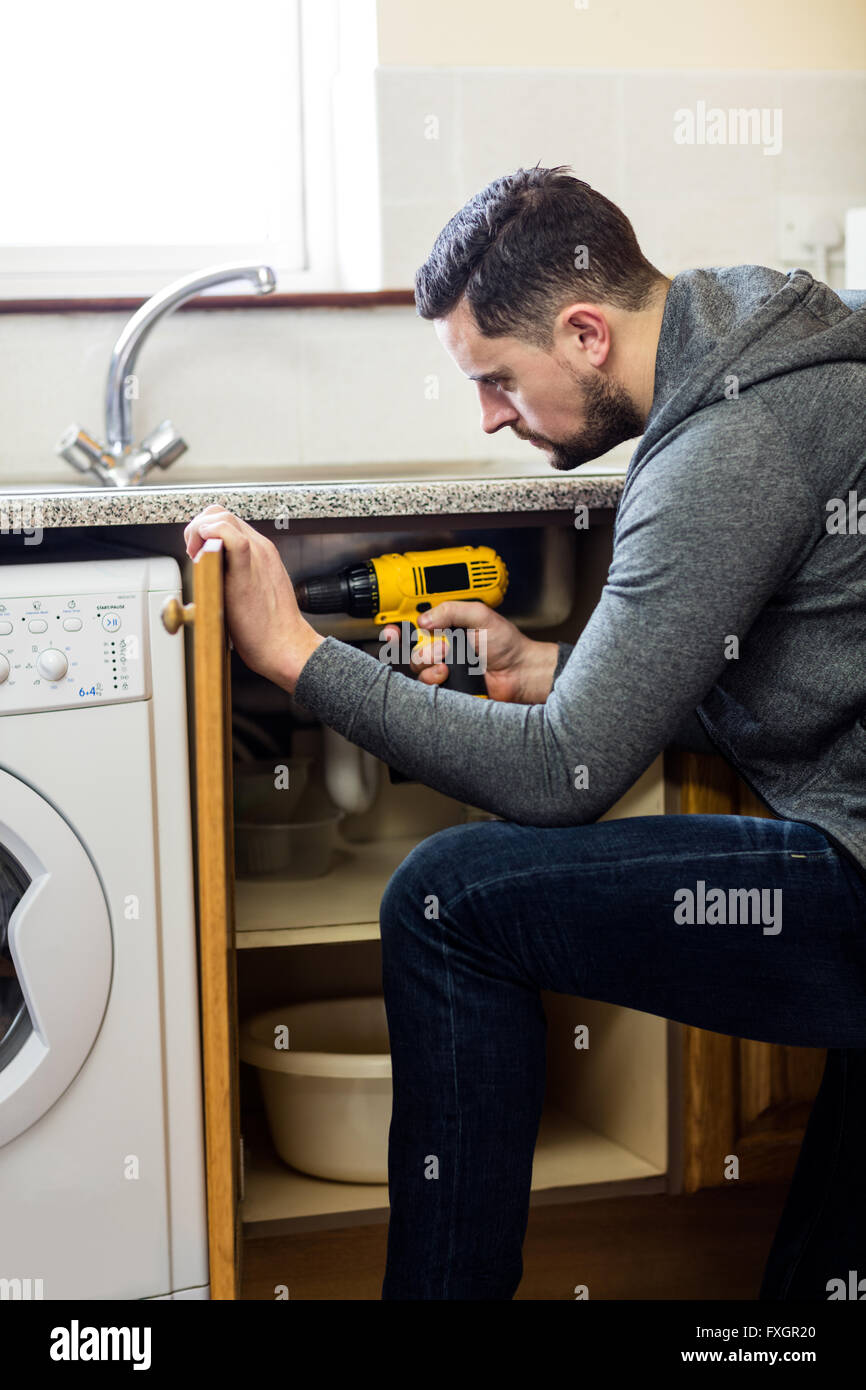 Manual worker drilling a hole in kitchen Stock Photo