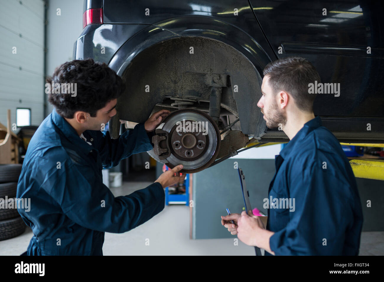 Mechanics examining car brake Stock Photo Alamy