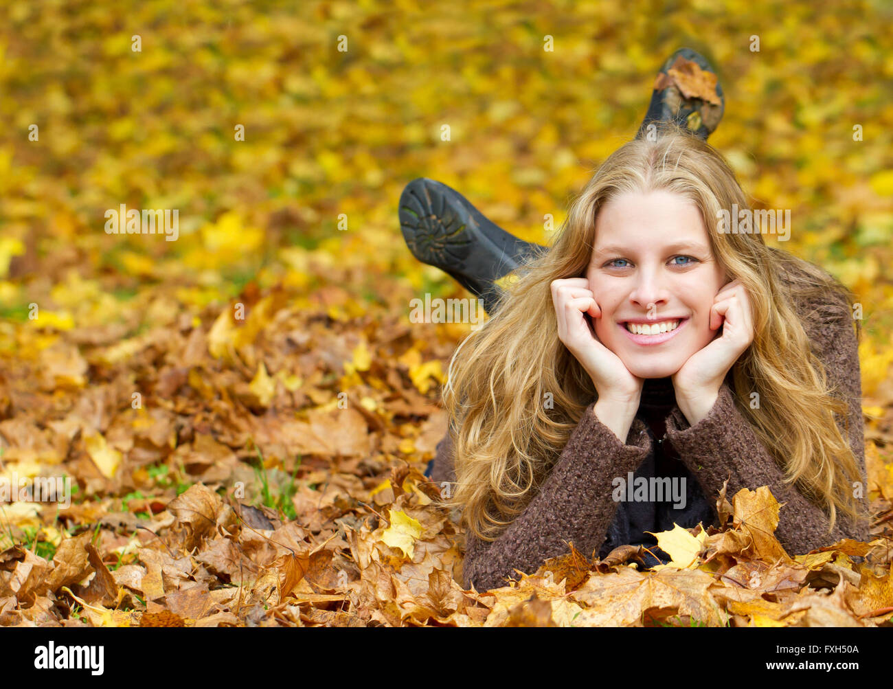 Young woman lying on meadow with autumn leaves Stock Photo - Alamy