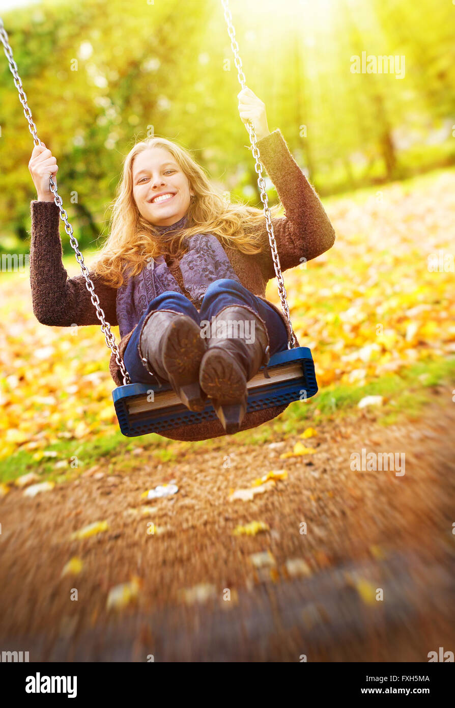 Happy young woman on a swing in the sun Stock Photo