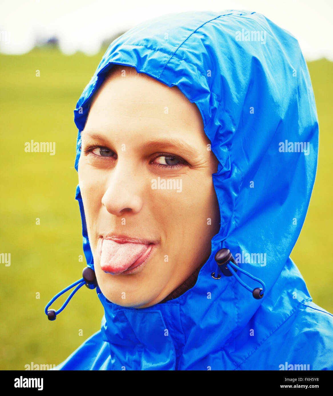 Young woman sticking tongue out on a rainy day Stock Photo