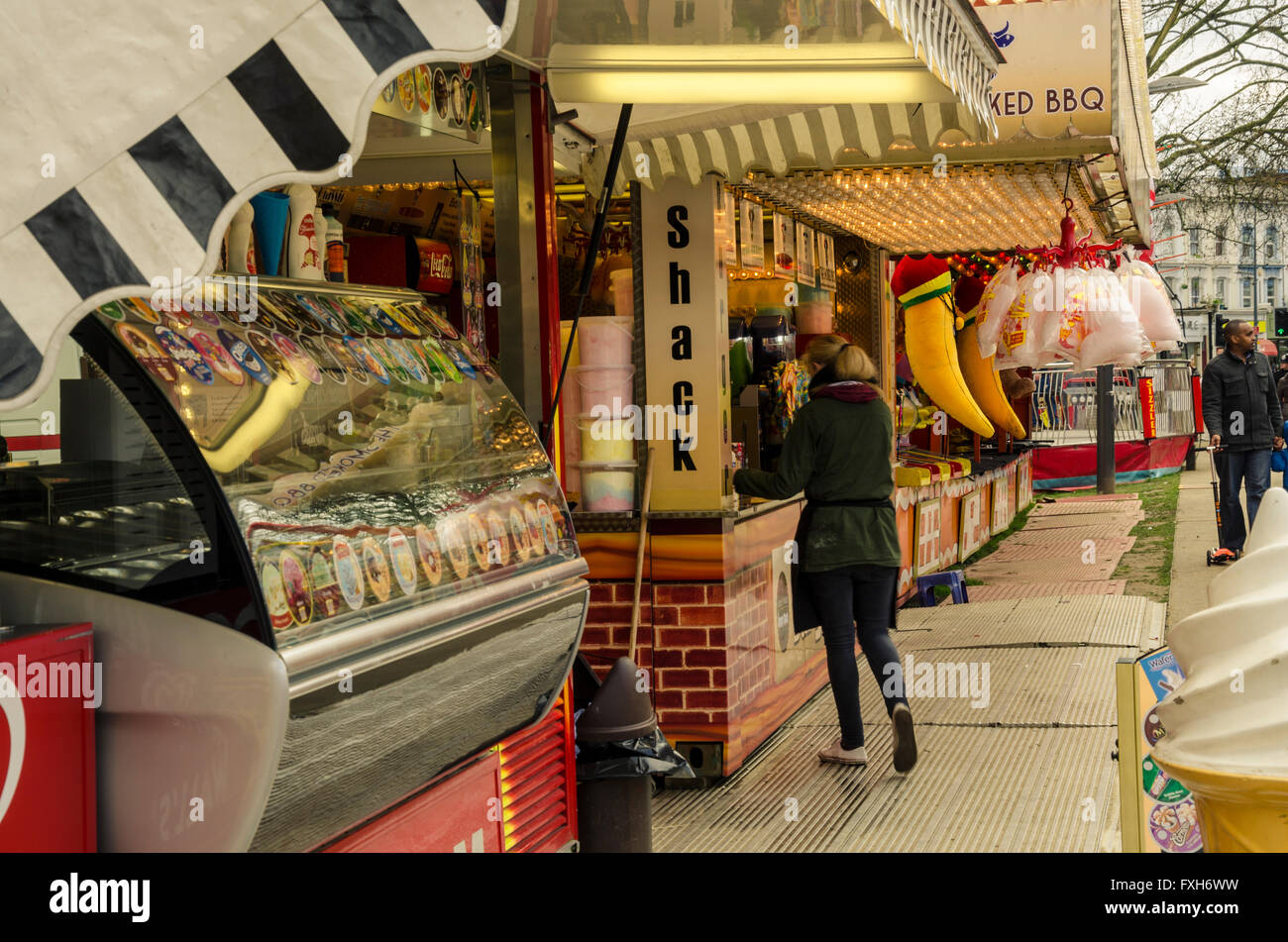 A woman buys refreshments at a snack kiosk at a funfair. Stock Photo