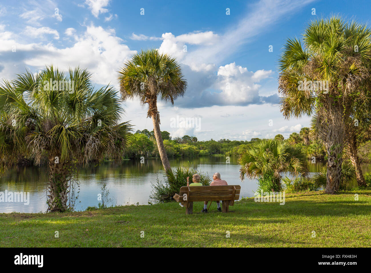 Couple sitting on bench overlooking water in Deer Prairie Creek in Deer Prairie Creek Preserve in Venice Florida Stock Photo