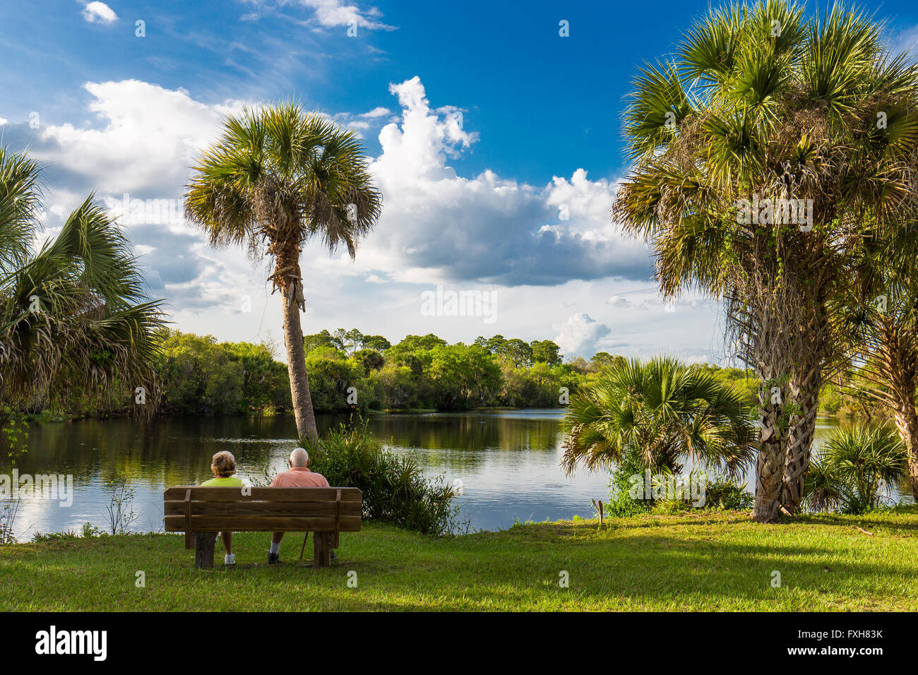 Couple sitting on bench overlooking water in Deer Prairie Creek in Deer Prairie Creek Preserve in Venice Florida Stock Photo