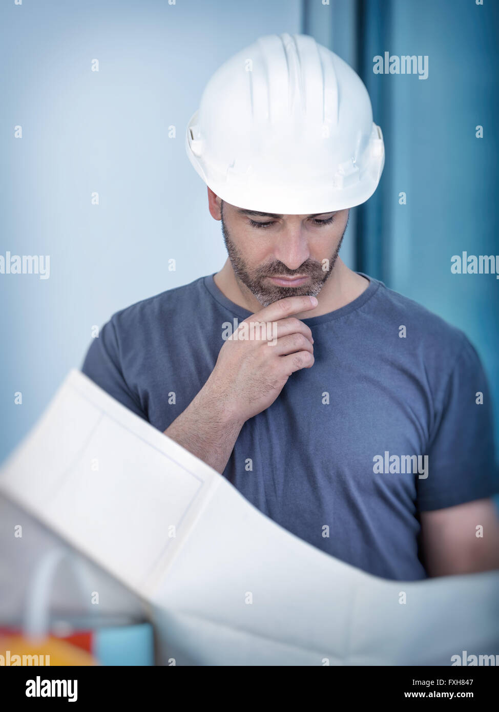 Portrait of an architect builder studying layout plan of the rooms, civil engineer working with documents on construction site Stock Photo
