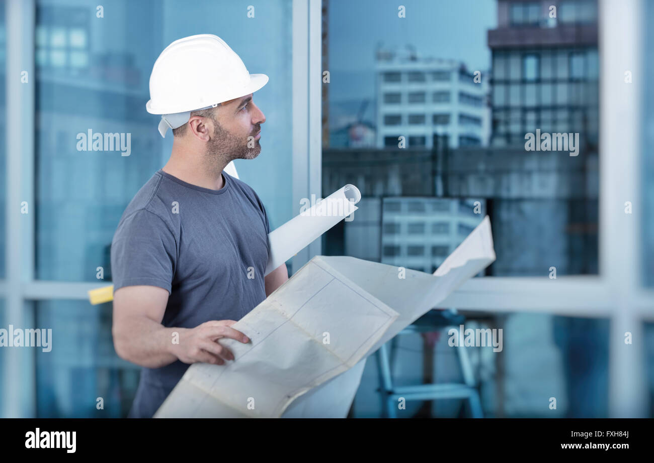 Portrait of an architect builder studying layout plan of the rooms, civil engineer working with documents on construction site Stock Photo