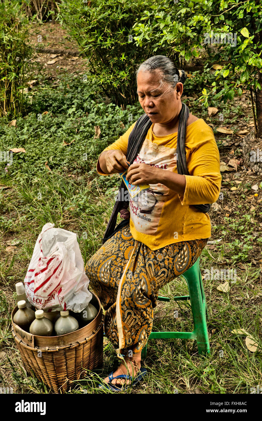 A Javanese woman seller of jamu, traditional Indonesian medicine, which she makes herself from herbs. Stock Photo
