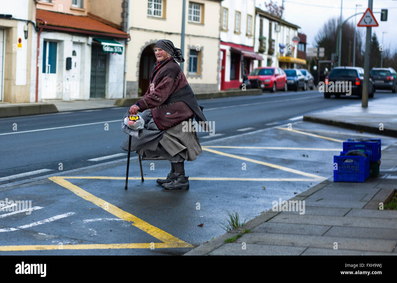 SANTIAGO DE COMPOSTELA CITY, SPAIN - DEC 22: Spain northern cold winter. An old woman in urban outdoor scene waiting the bus aft Stock Photo
