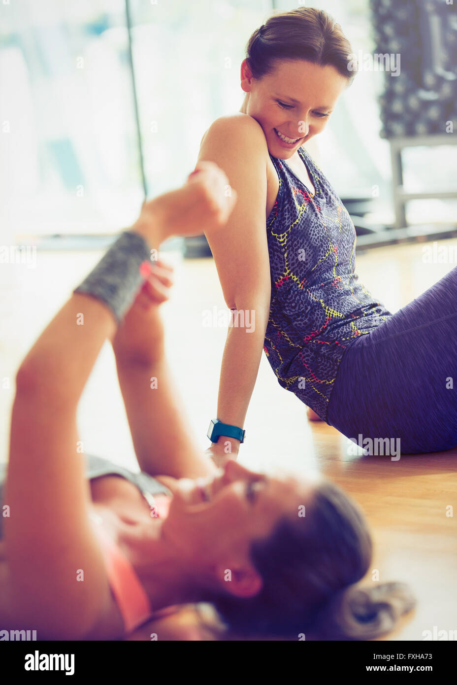 Smiling women resting on gym studio floor Stock Photo