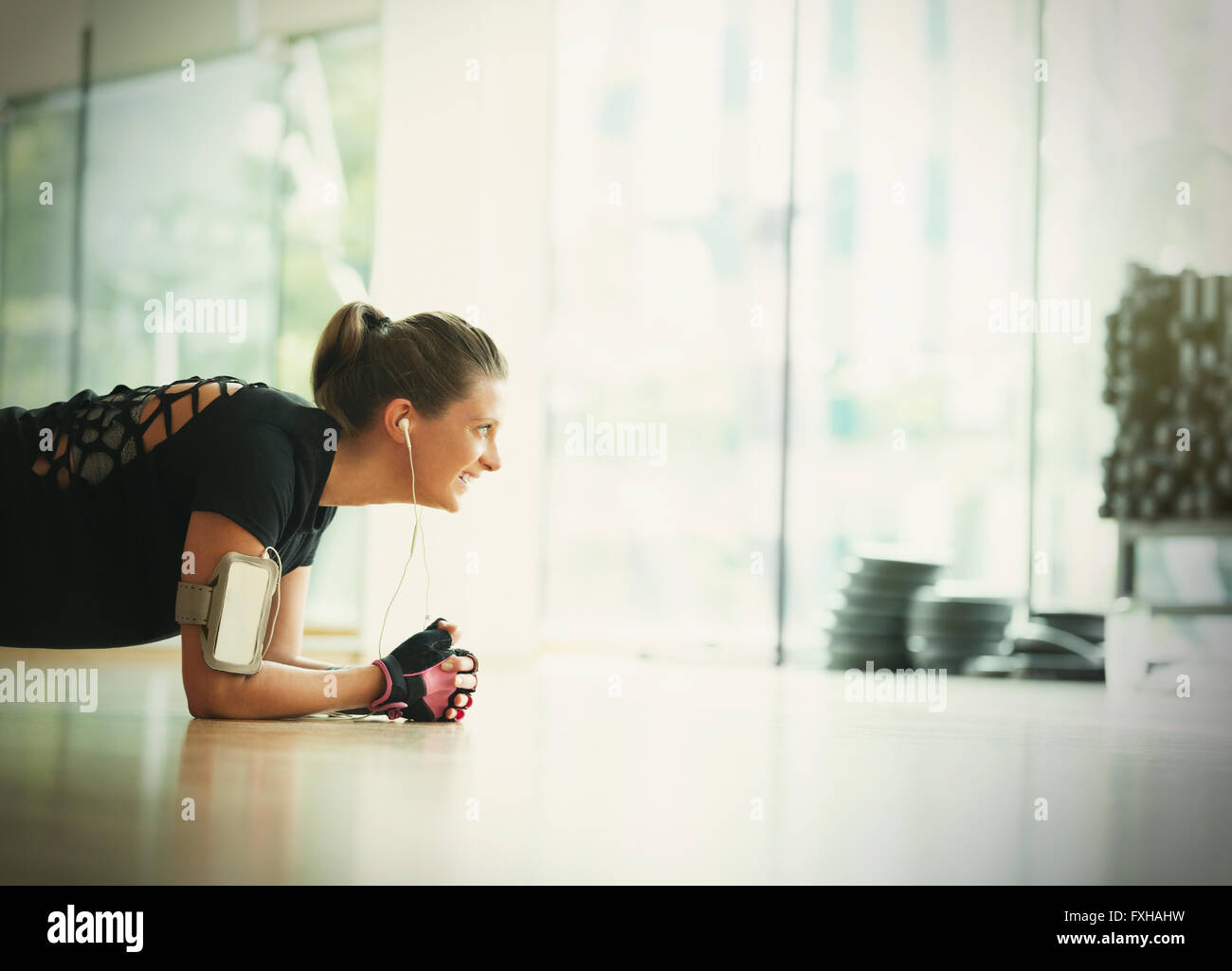 Smiling woman in plank position on gym studio floor Stock Photo