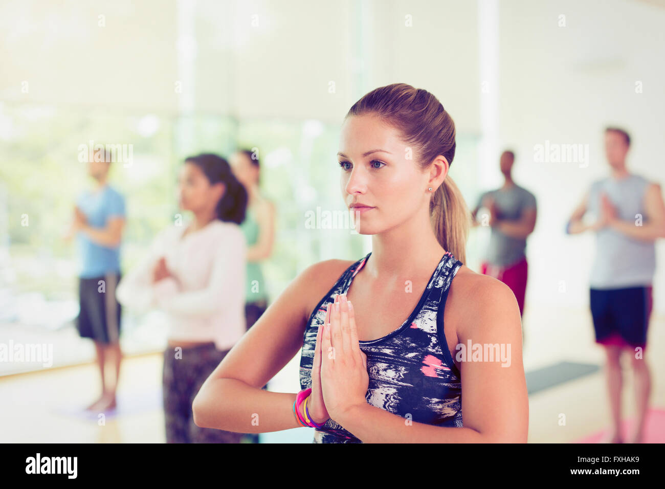 Focused woman with hands at prayer position in yoga class Stock Photo